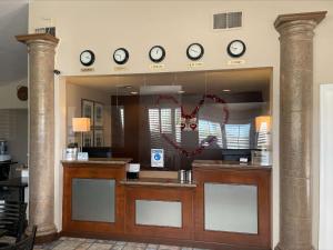 a hotel reception counter with clocks on the wall at SureStayPlus Hotel by Best Western San Jose Central City in San Jose