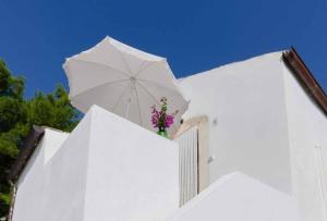 a white building with a white umbrella and flowers on it at Agriturismo Madonna Incoronata in Mattinata