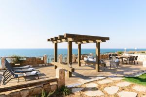 a wooden deck with a gazebo next to the ocean at Luxury Villa over the Cliffs & Wild Beach by FeelHome in Bet Yannay