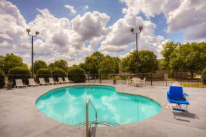 uma piscina com uma cadeira azul e cadeiras em Comfort Suites Pineville - Ballantyne Area em Charlotte