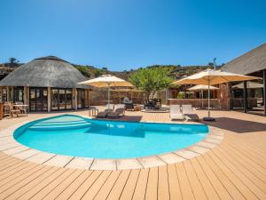 a large swimming pool with chairs and umbrellas at Mont Eco Game Reserve in Montagu