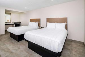 a hotel room with two beds with white sheets at Super 8 by Wyndham Bakersfield CA in Bakersfield