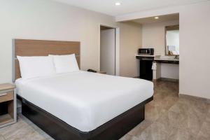 a large white bed in a room with a kitchen at Super 8 by Wyndham Bakersfield CA in Bakersfield