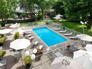 - une vue sur la piscine bordée de chaises et de parasols dans l'établissement ibis Styles Besançon, à Besançon