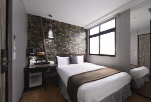a bedroom with two beds and a desk and a window at Herb Art Hotel in Keelung