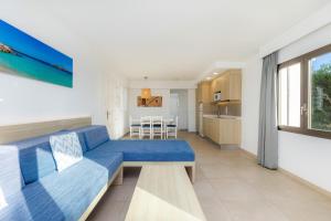 a living room with a blue couch and a kitchen at Apartamento Aquamarina 5 in Cala Ferrera
