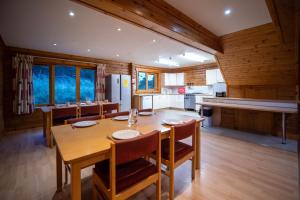cocina y comedor con mesa de madera y sillas en Badaguish forest lodges and camping pods, en Aviemore