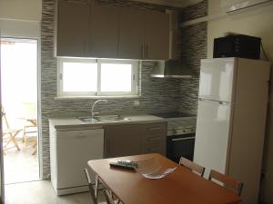 a kitchen with a table and a white refrigerator at Casa Verão Azul in Monte Gordo