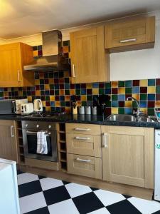 a kitchen with wooden cabinets and a checkered floor at Quirky studio flat selfcontained in London