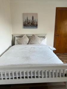 Cama blanca con sábanas y almohadas blancas en Quirky studio flat selfcontained, en Londres
