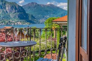 een balkon met een tafel en uitzicht op de bergen bij Villa Gard by Wonderful Italy in Bellagio