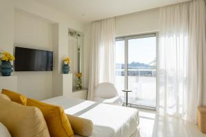 Schlafzimmer mit einem Bett, einem TV und einem Fenster in der Unterkunft Apollo Palm Hotel in Athen