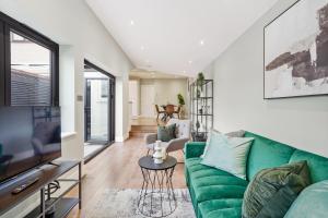 sala de estar con sofá verde y TV en Fabulous Wimbledon 3 Bed Apartment with Outside Space, en Londres