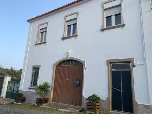 uma casa branca com uma porta castanha e duas janelas em Andar tranquilo entre Lisboa Sintra em Sintra