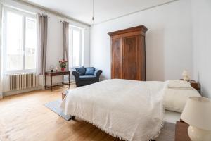 um quarto branco com uma cama e uma cadeira em LaConciergerieJonzac, Maison de Ville La Coquette em Jonzac