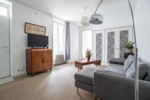 Una sala de estar con un sofá y un televisor. en Maison de Ville avec Jardin "La Coquette", en Jonzac