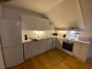 a white kitchen with white appliances and wooden floors at Rooftop view apartment in Vardø