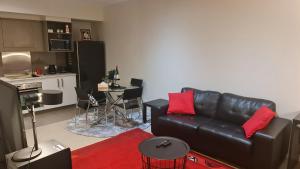 a living room with a black leather couch and a kitchen at Qure Restaurant and Apartments Canberra Bruce in Canberra