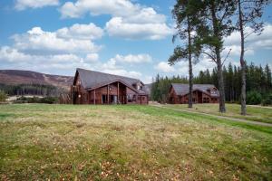 a house on a grassy field with a house at Badaguish forest lodges and camping pods in Aviemore