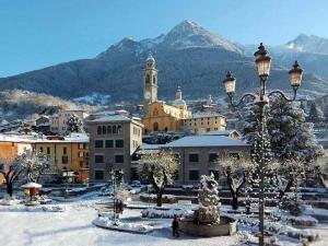 Eine Stadt im Schnee mit einem Weihnachtsbaum und einem Straßenlicht in der Unterkunft La Maison di Gabriella e Alfredo in Edolo