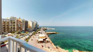 uma vista para uma praia com edifícios e o oceano em 6th floor seafront apartment with open sea views em Sliema