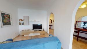 uma sala de estar com um sofá azul e uma televisão em 6th floor seafront apartment with open sea views em Sliema