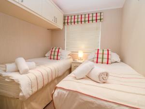 two twin beds in a small room with a window at Highfield Lodge in Windermere