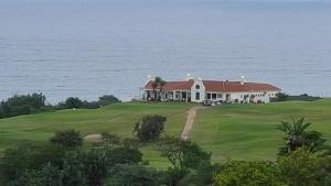 a large white house on a golf course next to the ocean at Syringa Sea View in Pennington