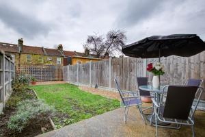 a table and chairs with an umbrella in a backyard at Statera Apartments - 2-Bed House in Stratford in London