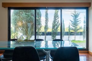 a glass table with chairs in front of a large window at Azores Green Woods Villa in São Vicente Ferreira