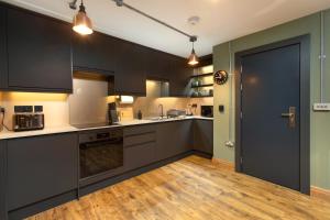 a kitchen with black cabinets and a wooden floor at The Duke in Trowbridge