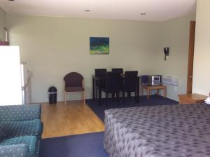 a hotel room with a bed and a table and chairs at ASURE Kapiti Court Motel in Paraparaumu Beach