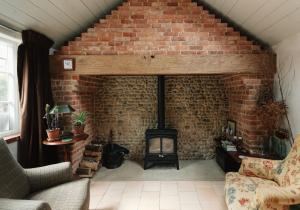 a living room with a brick wall and a fireplace at Spinks Nest in Hunworth