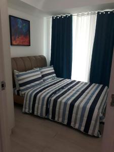 um quarto com uma cama com riscas azuis e brancas em Staycation at Azure by Melissa em Manila