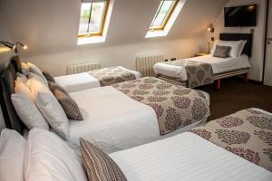 Un grupo de camas en una habitación con ventanas en The Rostrevor Inn, en Rostrevor