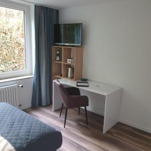 a room with a desk with a chair and a television at Kurparkhotel-Gemünd in Gemünd