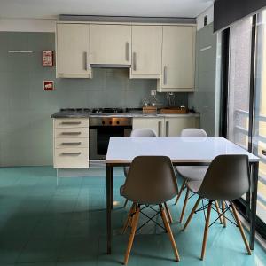a kitchen with white cabinets and a table and chairs at Apartamento Central Antero de Quental in Ponta Delgada