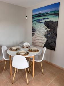 a dining room with a white table and chairs at Casa Esmeralda in Corralejo