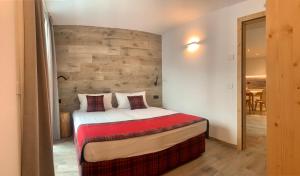 a bedroom with a bed with a wooden wall at Al Bait Ross in Bormio