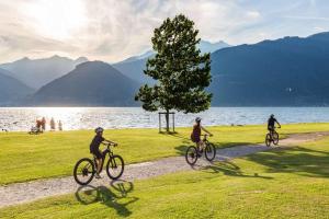 three people riding bikes on a path by the water at Seven Park Hotel Lake Como - Adults Only in Colico