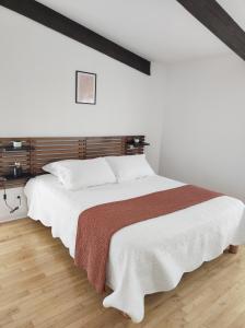 sypialnia z dużym białym łóżkiem z drewnianym zagłówkiem w obiekcie Lou Cantou w mieście Nègrepelisse