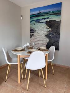 un comedor con mesa, sillas y una pintura en Casa Esmeralda, en Corralejo