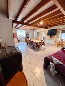 uma sala de jantar com mesa e cadeiras e uma televisão em Gîte Le Rouge Queue 3 étoiles em Fresnes