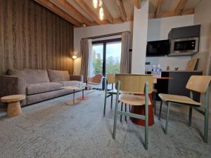 ein Wohnzimmer mit einem Sofa, einem Tisch und Stühlen in der Unterkunft Domaine de l'Epau Eco-Resort - Eco-Lodges in Yvré-lʼÉvêque