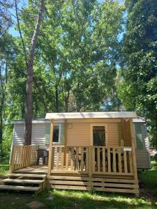 a tiny house with a porch and a tree at Famille Peeters in Camiers