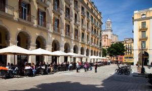 a group of people sitting at tables in a city street at Aeris Boutique Studio in Girona