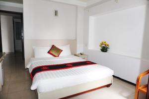 1 dormitorio con cama blanca y almohada roja en Le Duong Hotel, en Nha Trang