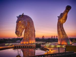 dos estatuas de caballos se iluminan al atardecer en The Grange Manor, en Grangemouth