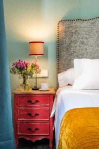 um quarto com uma cama e uma cómoda vermelha com um candeeiro em Casas De Adriano em Sevilha