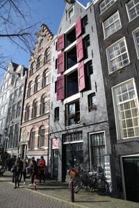 ein Gebäude mit rosa Fenstern auf einer Stadtstraße in der Unterkunft International Budget Hostel City Center in Amsterdam
